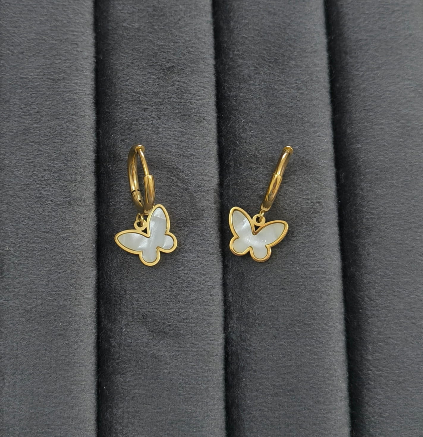 Butterfly-shaped earrings with gold accents on a gray background