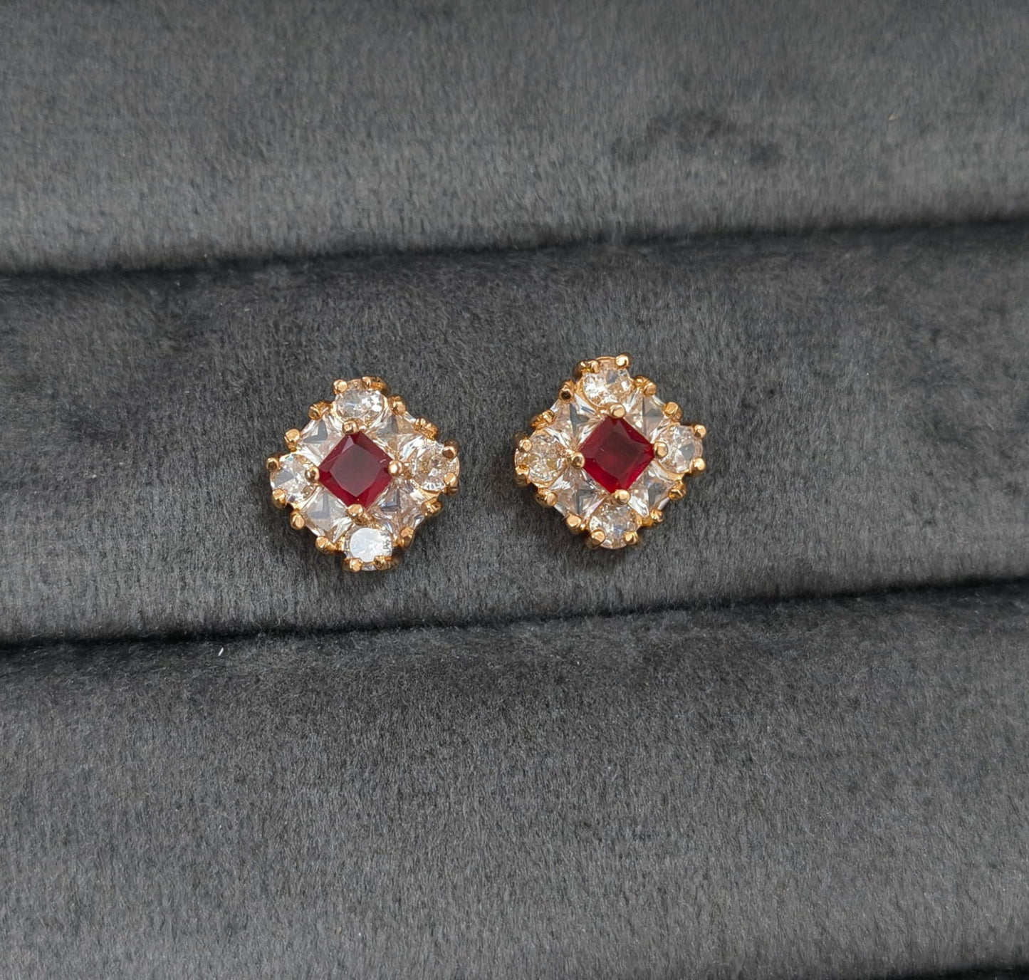 Pair of earrings with red gemstones on a gray fabric background