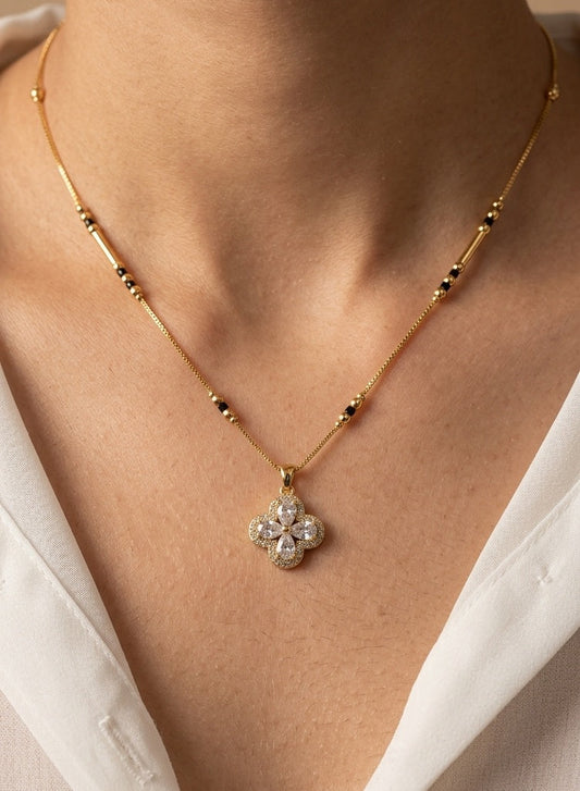 Close-up of a premium 18K gold-plated anti-tarnish clover Mangalsutra necklace with AD stones, featuring a delicate chain and lobster clasp closure, displayed on a minimalist jewelry pad.